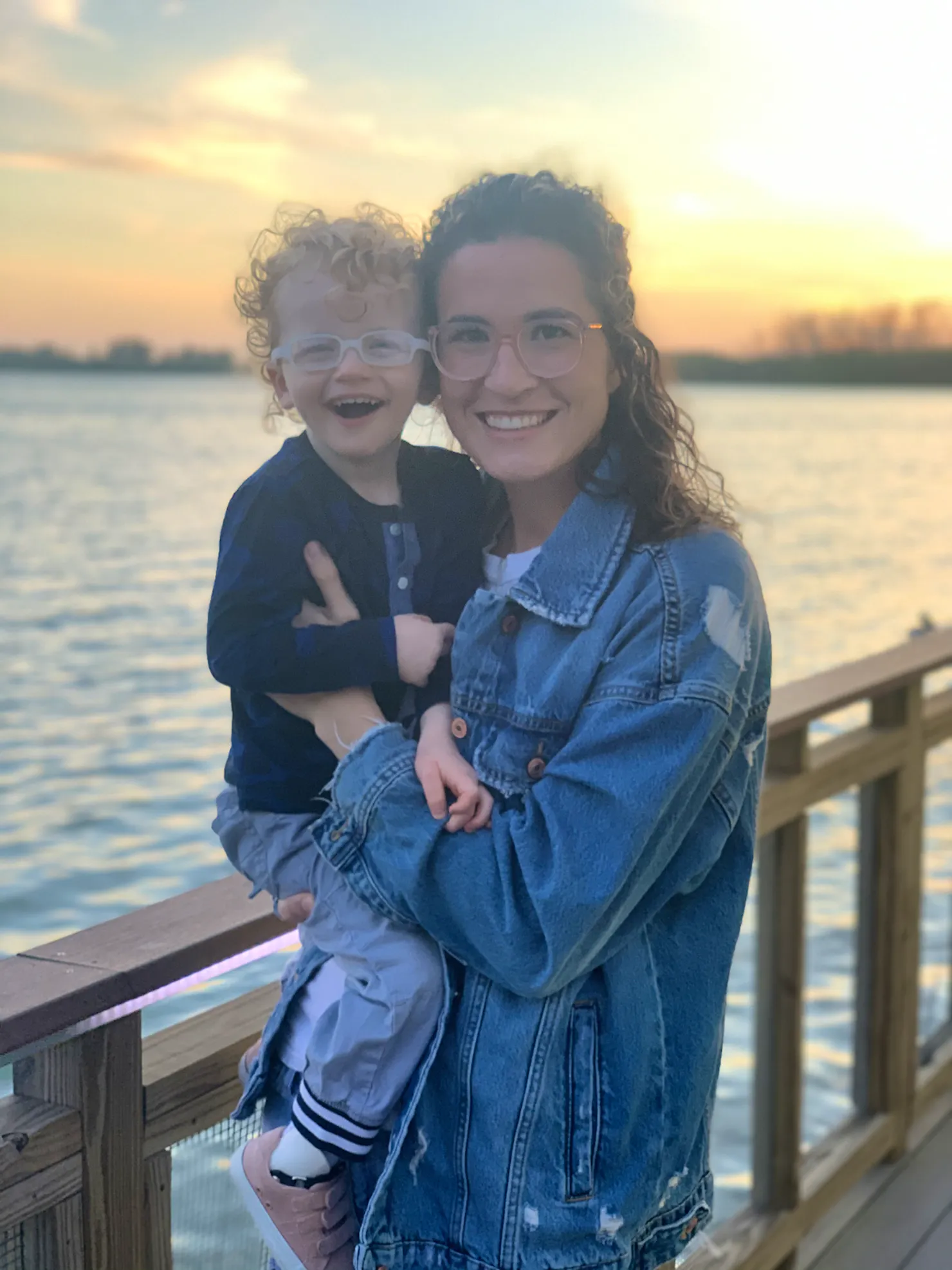 Sarah Shiffman holding her son Emerson on a lakeside dock at sunset, both smiling