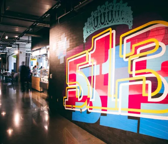 Colorful 513 mural with a crown on a brick wall inside the On the Rhine Eatery food hall