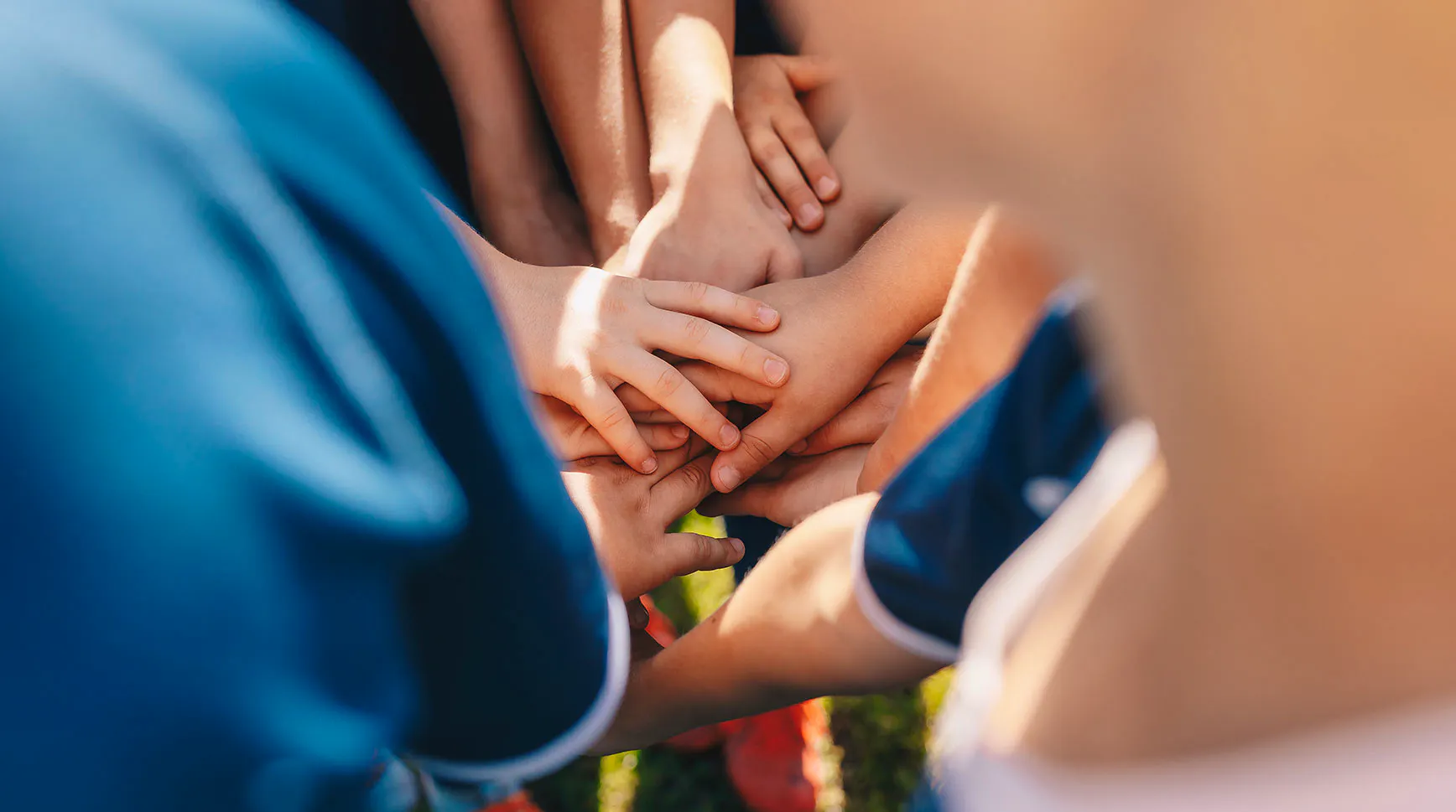 Close-up of youth sports teammates stacking their hands together in a huddle