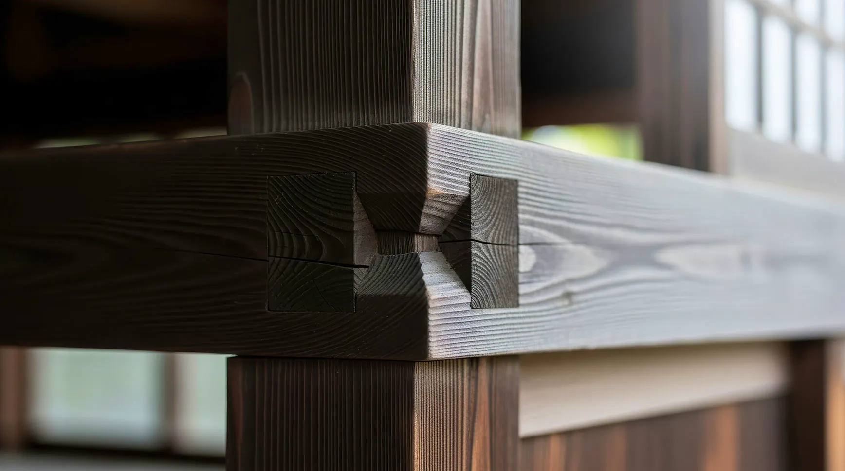 Close-up of a dark timber post and beam locked together with a tight mortise-and-tenon joint